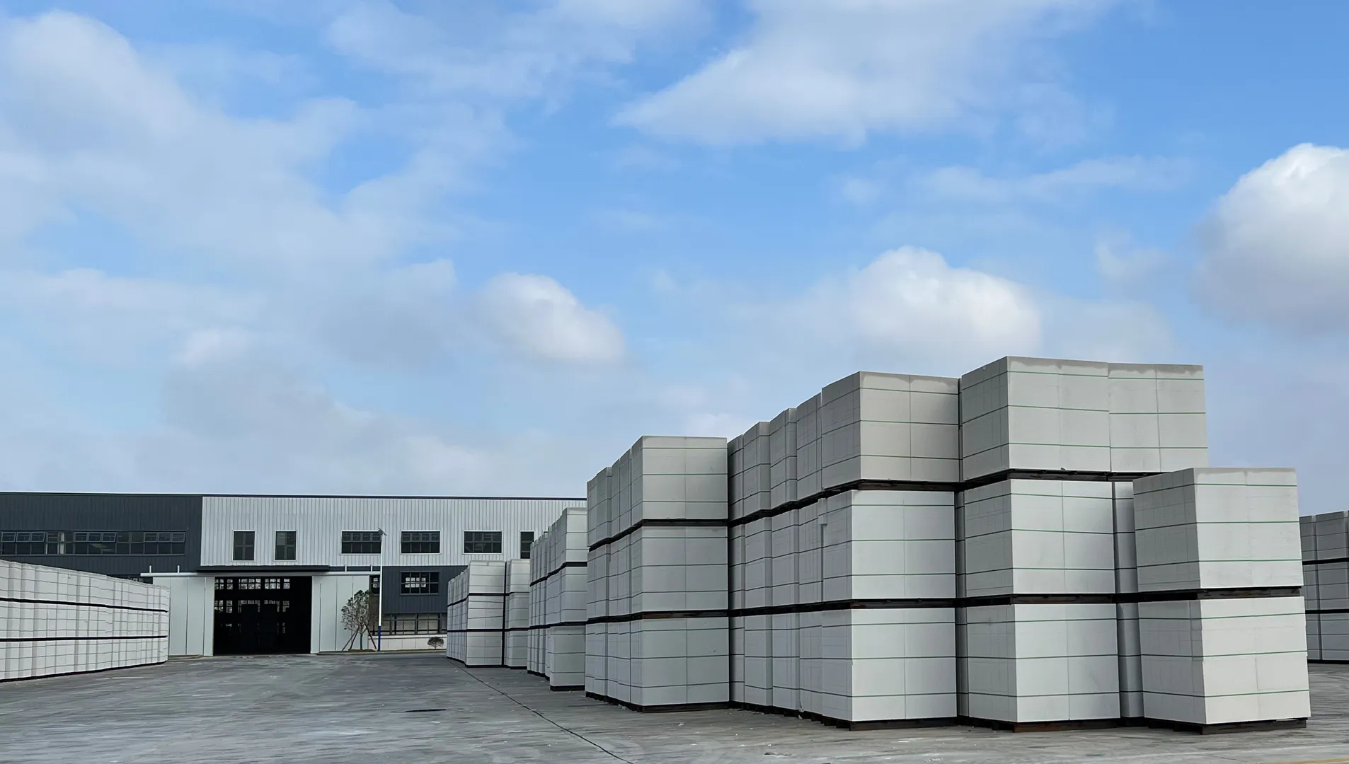 Large stacks of precast concrete wall panels and building components stored in an outdoor precast concrete manufacturing facility.